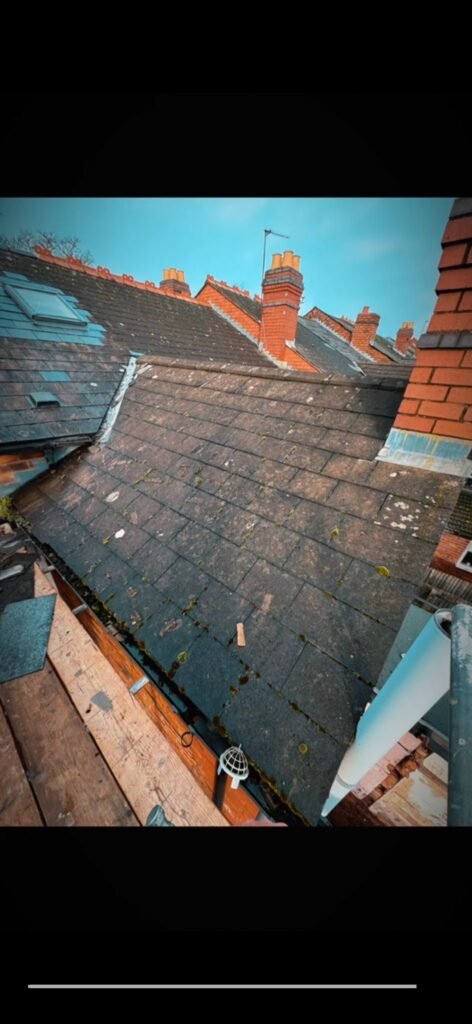 Worn moss-covered tiled roof before replacement on a London terraced house